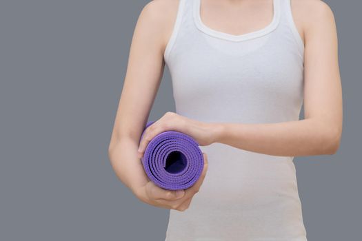 Young asian woman holding her yoga mat at yoga healthy sport gym. Yoga and meditation have good benefits for health. Photo concept for Yoga Sport and Healthy lifestyle