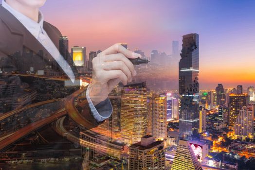 Double exposure Young and Smart business woman holds a marker writing in air with real estate building in background. Elegant Design for smart business and smart technology concept