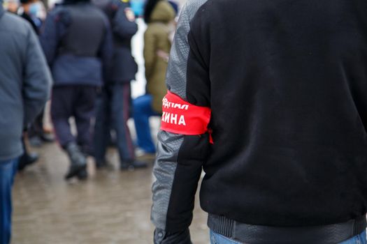 civillian man with red armband signed people's squad in russian - standing in crowd, close-up with selective focus and background blur