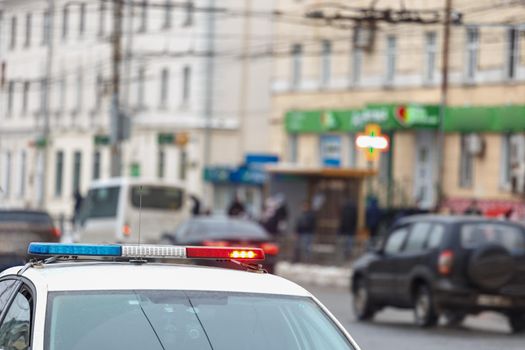 police car lights in city street with civilian cars traffic in blurry background in Tula, Russia.