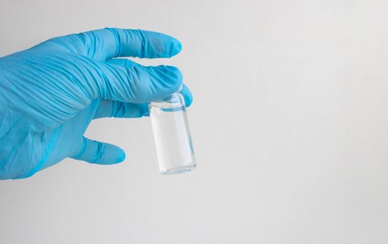 A blue-gloved hand holds a bottle of vaccine.The concept of coronavirus, medicine and medicines.
