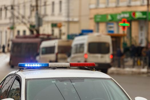 police car lights in city street with civilian cars traffic in blurry background in Tula, Russia.