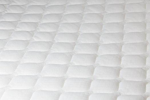 Soft white mattress close-up background with selective focus and blur.