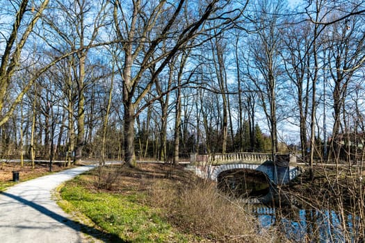 Sunny morning in park with small river and concrete bridge