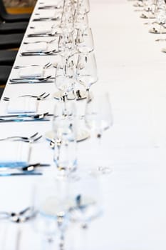 Long table with white tablecloth full of tableware prepared for lunch