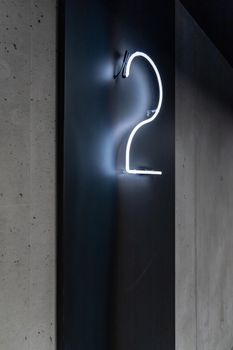 Neon sign with glowing white number 2 on black panel
