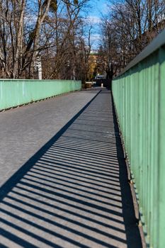 Long narrow concrete bridge with green metal railings on both sides