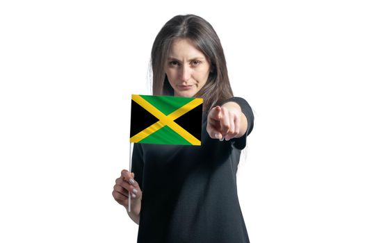 Happy young white woman holding flag of Jamaica and points forward in front of him isolated on a white background.