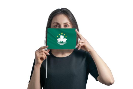 Happy young white woman holding flag Macau flag and covers her face with it isolated on a white background.