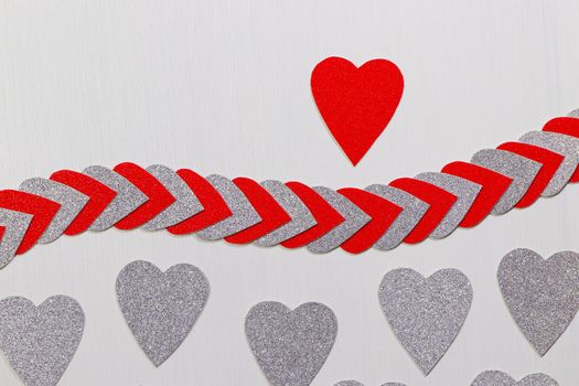 Saint Valentine's day red heart above heart string with silver hearts on textured white background