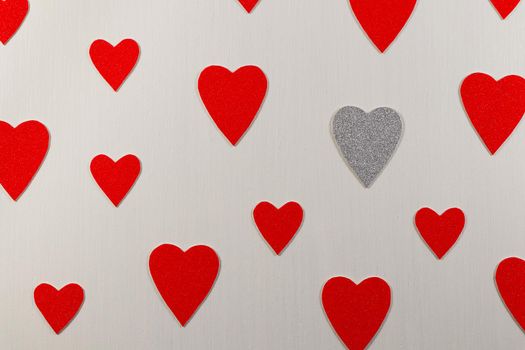 Saint Valentine's day silver heart amongst red hearts on textured white background