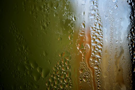 Condensation with beaded moisture droplets on the outside of a cold glass or bottle in a close up full frame background texture