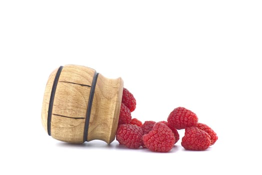 Heap of red ripe raspberry berries fall out of a wooden container isolated on white background