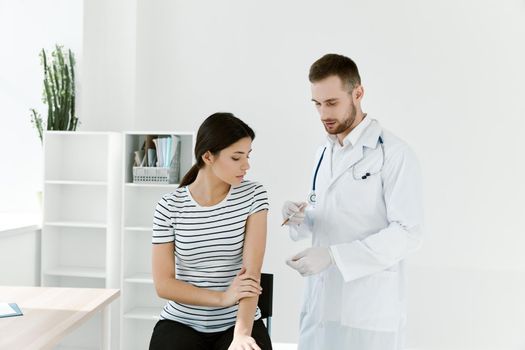 male doctor in a white coat giving an injection to a woman in a hospital. High quality photo