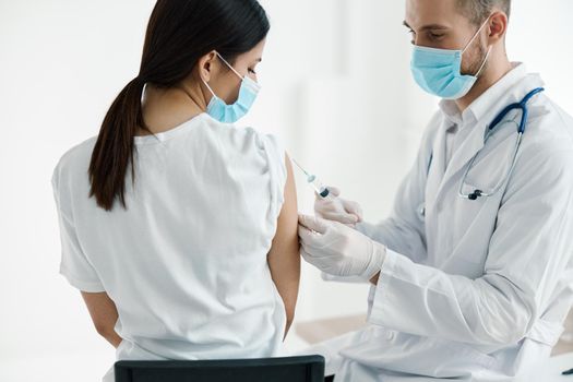 doctor in medical mask injecting vaccine on woman's shoulder epidemic hospital. High quality photo