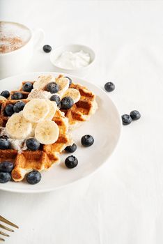 High angle view of waffles with blueberries, banana and yoghurt