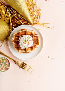 Birthday party waffles decorated with youghurt and colorful sprinkles, top view flat lay