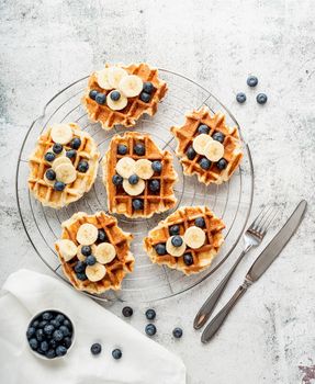 Top view of fresh made waffles with blueberries, banana and yoghurt, flat lay