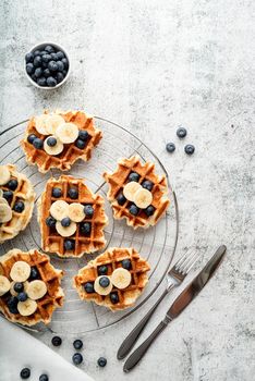 Top view of fresh made waffles with blueberries, banana and yoghurt, flat lay