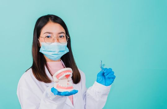 Asian beautiful woman dentist holding silicone orthodontic retainers and model teeth denture isolated on blue background, Teeth retaining tools after removable braces, Orthodontics dental healthy care