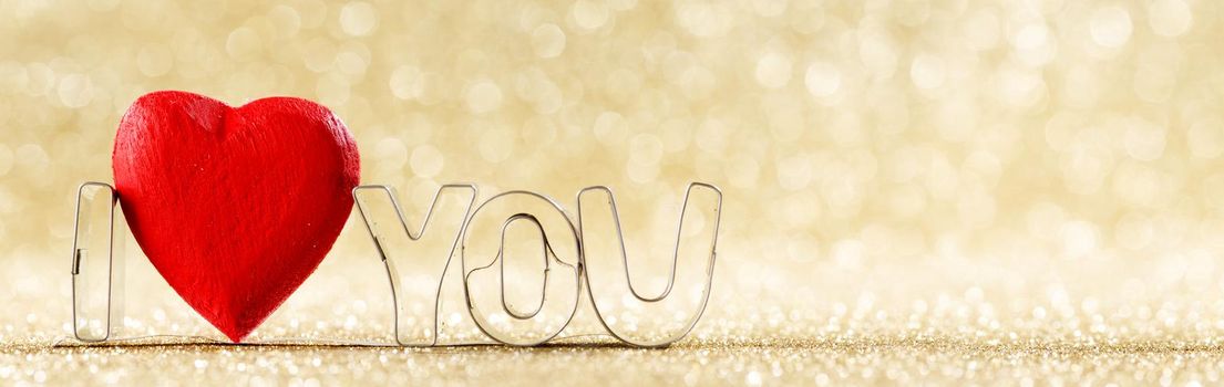 I love you and red handmade wooden heart on golden bright glitter lights bokeh background