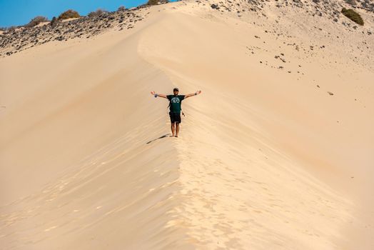 Sotovento, Fuerteventura, Spain: 2020 October 8: Young man walks through the dunes at Playa de Sotavento, Fuerteventura in Spain in summer.