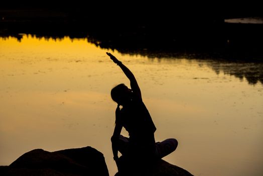 Silhouettes of a woman doing yoga at sunset.