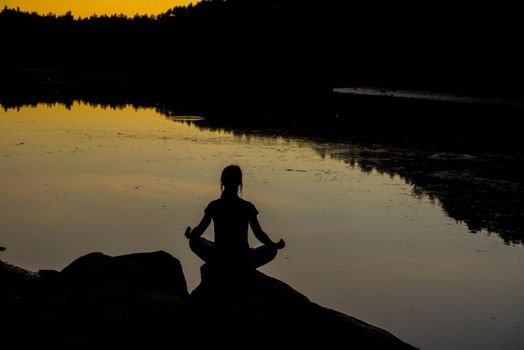 Silhouettes of a woman doing yoga at sunset.