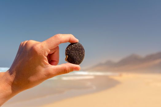 Person with stone on the virgin beaches on the island of Fuerteventura. Cofete beach on the island of Fuerteventura, Spain.