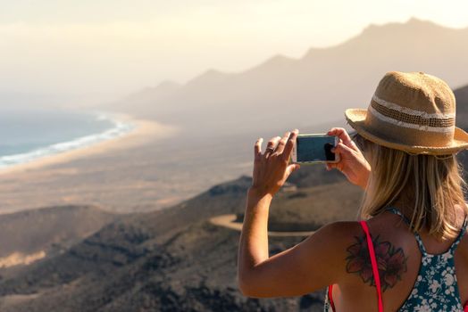 Cofete, Spain: 2020 october 7: Blonde Girl takes a photo to the Landscape of the Cofete Beaches in Fuerteventura, Spain.