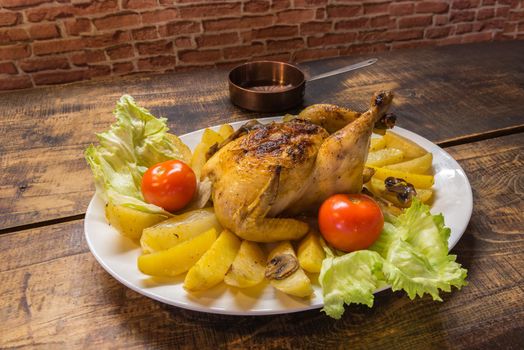 Chicken plate with potatoes with rustic wooden background.