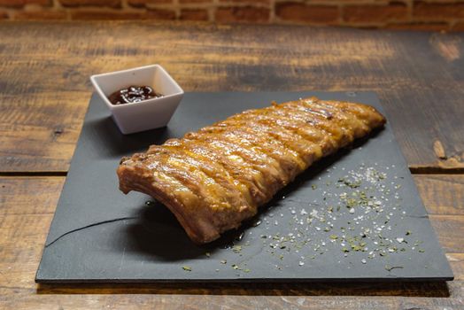Caramelized lamb ribs on a rustic wooden background.