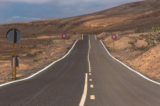 Winding road through the dunes of Corralejo desert with volcano in the background, in Fuerteventura, Canary Islands, Spain.
