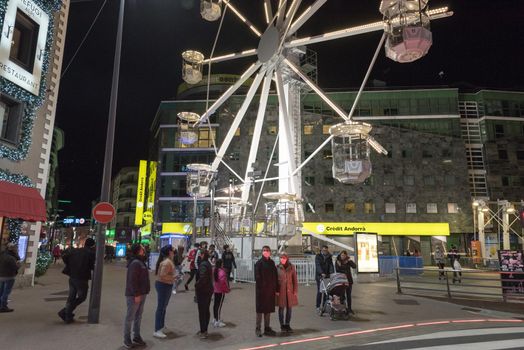 Andorra la Vella, Andorra : 2020 October 30 : People walk in the steet behind the Ferris wheel in the City of Andorra La Vella, capital of Andorra in the Pyrenees in autumn 2020.