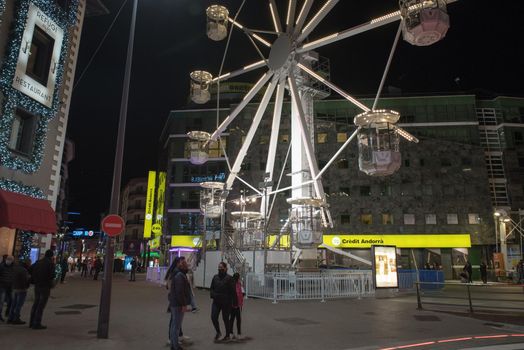 Andorra la Vella, Andorra : 2020 October 30 : People walk in the steet behind the Ferris wheel in the City of Andorra La Vella, capital of Andorra in the Pyrenees in autumn 2020.