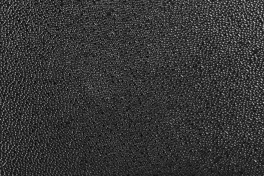 Rough black plastic finish microstructure with micro bubbles surface texture and flat and even background. Abstract dark background.