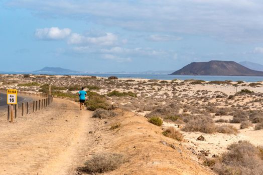 Corralejo, Fuerteventura, Spain: 2020 October 30: Young man running in the Dunas de Corralejo Natural Park in Fuerteventura, Spain in the fall of 2020.
