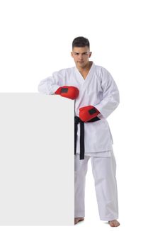 Full length portrait of man fighter training taekwondo with blank banner isolated on white background