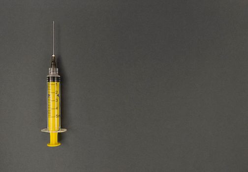 Yellow syringe on grey background. Simple flatlay with copy space.