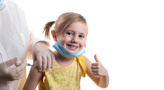 Doctor is vaccinating a young Caucasian girl in yellow dress showing thumb up isolated on white background