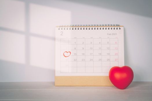 Calendar and heart shape with memo 14 February Valentine day on desk, reminder for surprise of love, romance and sweet, celebration and decoration, date and planner, nobody, top view, holiday concept.