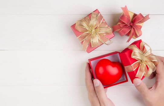 Valentine day, hand open red gift box with heart shape on wooden white background, celebration and anniversary with giving love, presents with romantic and surprise, holiday and festive concept.