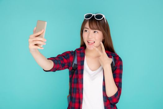 Beautiful portrait young asian woman cheerful smiling and take selfie on smart mobile phone, beauty girl wear travel summer enjoy and fun in vacation isolated on blue background, holiday concept.