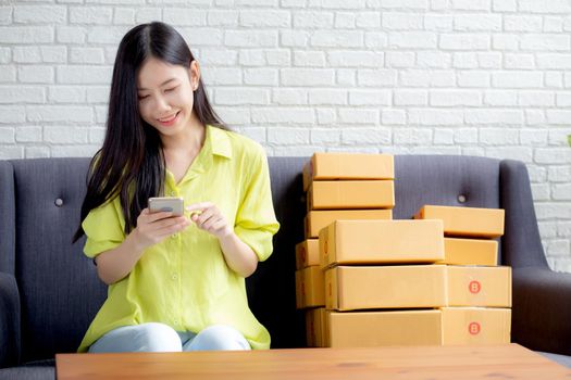 Young asian woman is entrepreneur check order from smartphone with customer while purchase online, logistic and delivery, online shopping, female is seller of business SME, merchant looking phone.