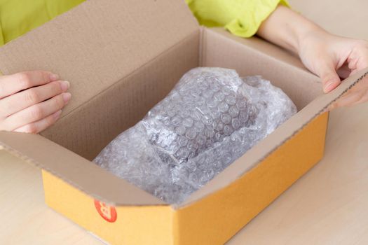 Closeup hand of woman opening parcel box with check product at home, female unpack with knife, delivery and shipping, shipment and express for shop, online shopping store and service concept.