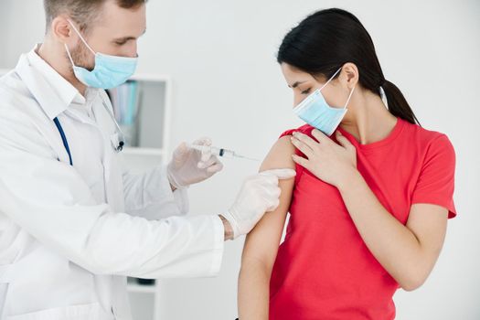 male doctor makes an injection into the arm of a patient wearing a medical mask. High quality photo