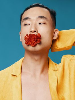 A man in a yellow jacket with a red flower in his mouth on a blue background. High quality photo