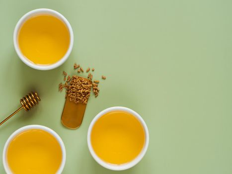 cups of buckwheat tea on light green background. Top view of healthy soba tea and groats of tartary buckwheat seeds on green paper background. Flat lay. Copy space