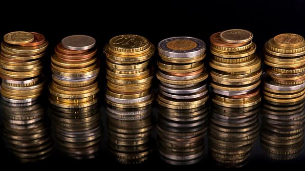 Stacks cf different country coins on black background.