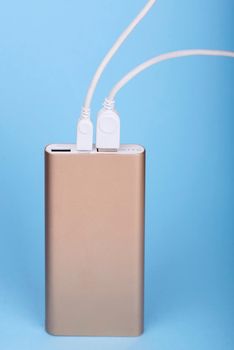 Smartphone charging with power bank on a blue background.